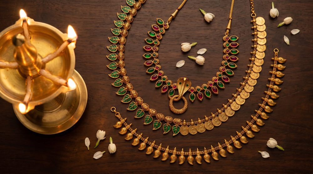 Flat-lay of traditional Kerala gold jewellery including Palakka Mala, Nagapadam, Kasu Mala and Manga Mala with jasmine and brass oil lamp
