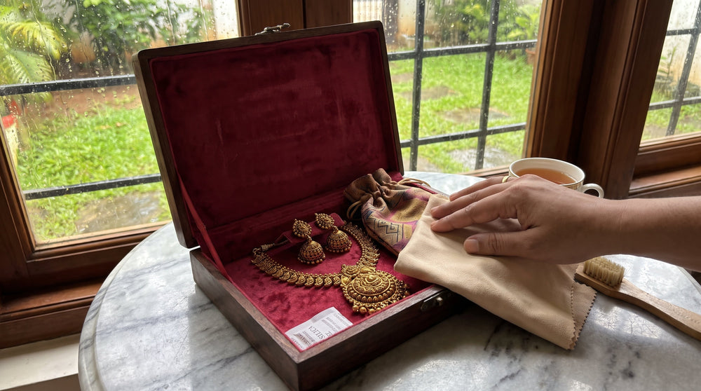 Antique gold South Indian temple necklace and jhumkas stored in a lined wooden jewellery box with microfibre cloth on a marble surface
